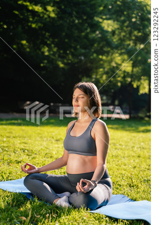 Young pregnant woman sitting on the mat with her eyes closed and meditating 123292245