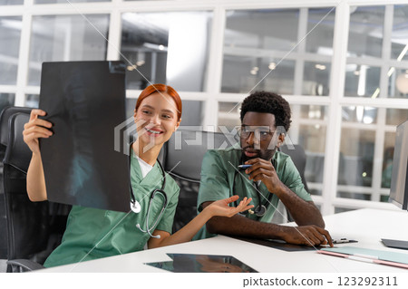 Woman doctor with redhead discussing bone care with diverse colleague in medical center 123292311