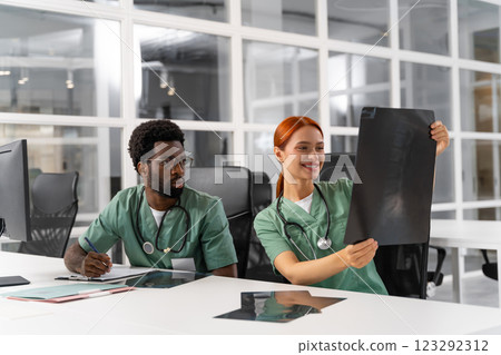 African American man doctor with redhead woman surgeon reading radiology scan together 123292312