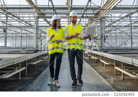 Two young caucasian engineers inspecting a greenhouse construction site 123292405