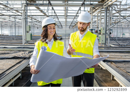 Engineers at the greenhouse construction site scrutinizing a construction plan Engineers at the greenhouse construction site scrutinizing a construction plan 123292899