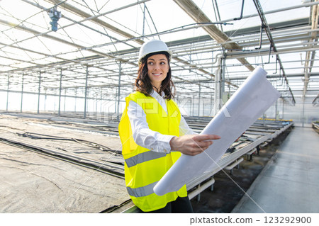 Engineers at the greenhouse construction site scrutinizing a construction plan 123292900