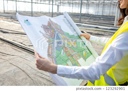Engineers at the greenhouse construction site scrutinizing a construction plan Engineers at the greenhouse construction site scrutinizing a construction plan 123292901