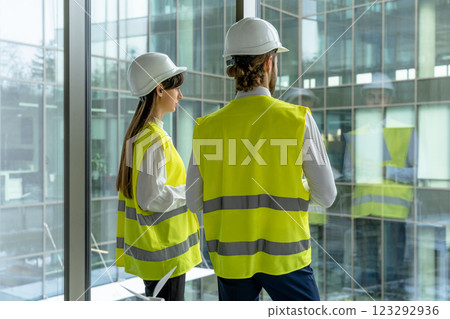 Two engineers in yellow vests standing at the panoramic window Two engineers in yellow vests standing at the panoramic window 123292936
