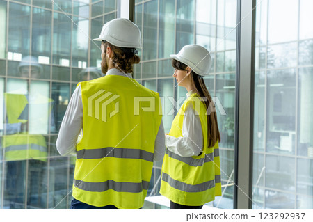 Two engineers in yellow vests standing at the panoramic window Two engineers in yellow vests standing at the panoramic window 123292937