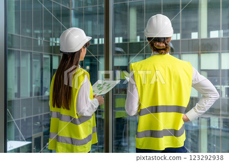 Two people in yellow vests and hard caps working together in the office Two people in yellow vests and hard caps working together in the office 123292938