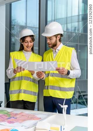 Two young engineers in yellow vests discussing new sustainability project Two young engineers in yellow vests discussing new sustainability project 123292960