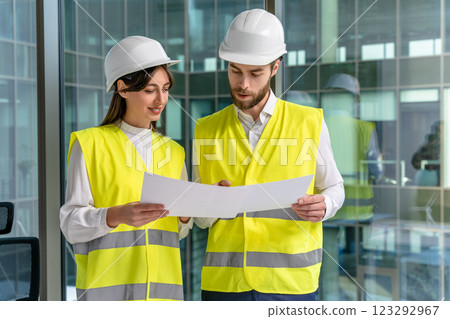 Two young engineers in yellow vests discussing new sustainability project Two young engineers in yellow vests discussing new sustainability project 123292967