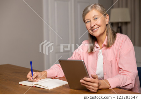 Smiling good-looking mid aged woman working on a laptop and looking involved 123293547