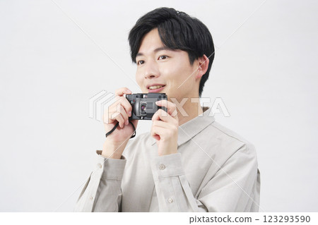 一名 20 多歲的男子拿著一台底片相機，背景為白色 123293590