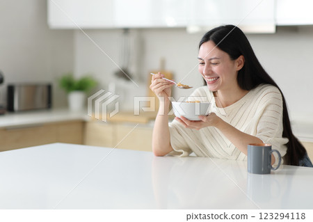 Asian woman eating cereals in a kitchen island 123294118