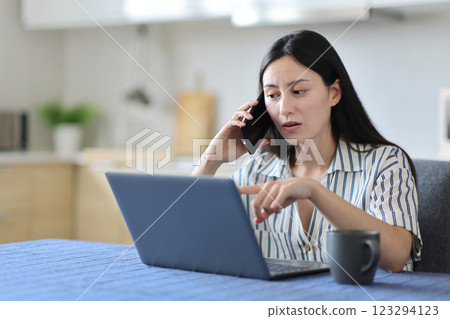 Asian woman talking on phone about laptop content at home 123294123