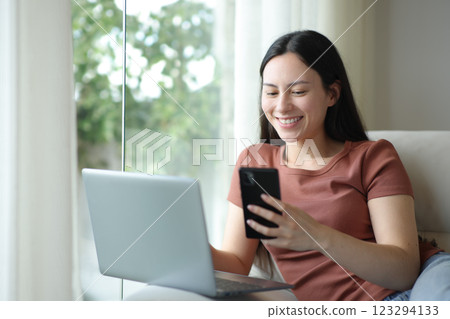 Happy asian woman using phone and laptop in ahouse Happy asian woman using phone and laptop in ahouse 123294133