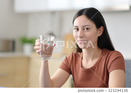 Serious asian woman holding glass of water at home Serious asian woman holding glass of water at home 123294136