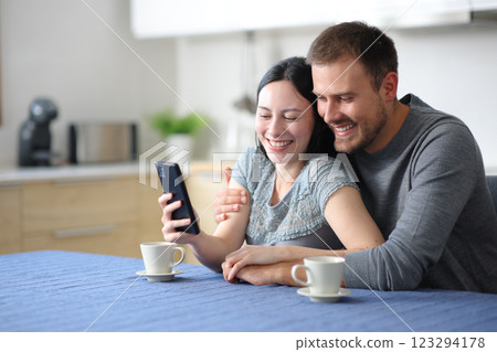Happy interracial couple in love checking phone Happy interracial couple in love checking phone 123294178