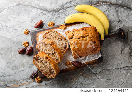 Freshly baked date banana walnuts bread loaf surrounded by ingredients close-up on wooden board. Horizontal top view 123294415