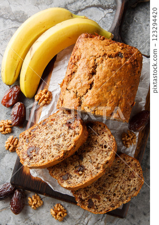 Vegetarian date banana walnuts bread loaf with honey and spices close-up on wooden board on table. Vertical top view Vegetarian date banana walnuts bread loaf with honey and spices close-up on wooden board on table. Vertical top view 123294420