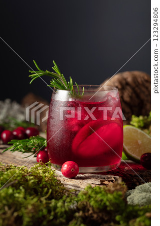 Cranberry cocktail with ice, lime, and rosemary on a old wooden board. 123294806