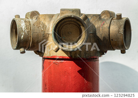 Close up of Red fire hydrant with Brass valve for Fire anticipation on land in front of an on white cement wall background. 123294825