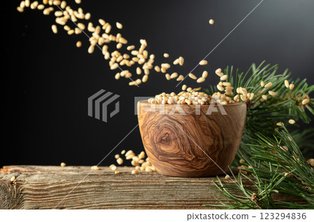 Nuts in a wooden bowl and cedar branch on a old wooden table. 123294836