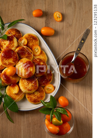 Delicious homemade pancakes with cottage cheese, kumquat jam and fruits on a wooden table, top view 123295138