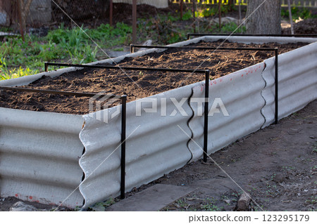 Permaculture raised warm bed made of slate with branches at the base in the garden 123295179