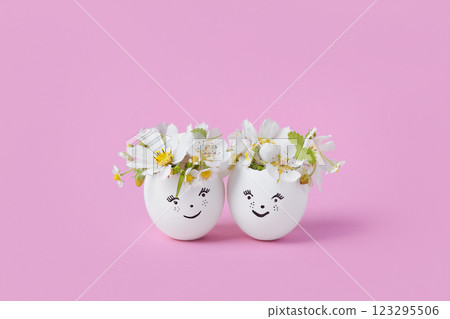 White eggs with funny face with spring pear and strawberry flowers on a pink background. Happy Easter concept. Greeting card. 123295506