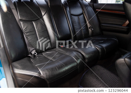 Clean after washing the rear passenger seats of matte black genuine leather inside the interior of an expensive SUV, preparation before selling the car. 123296044