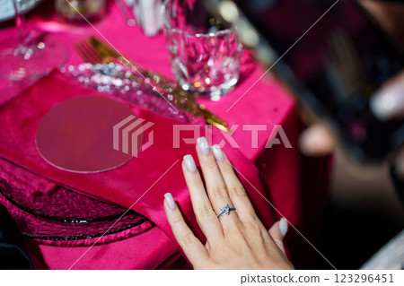 A woman's hand with a new ring. the background of a table with a red tablecloth A woman's hand with a new ring. the background of a table with a red tablecloth 123296451