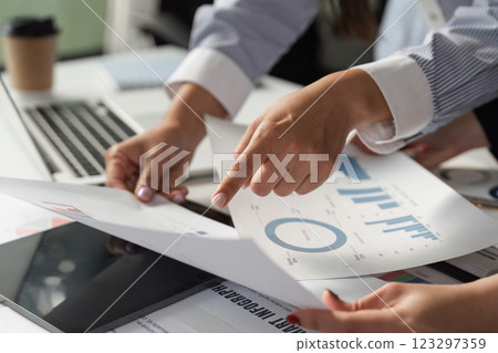 Business professionals reviewing financial documents and charts in a collaborative office environment. 123297359