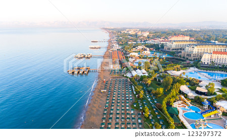 Aerial view of a luxurious beachfront resort with private piers, pools, and sunbeds along the coastline 123297372