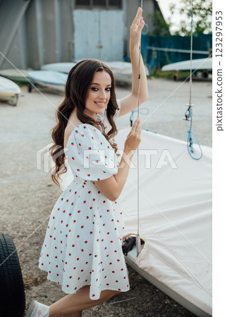 Beautiful brunette woman in summer dress by the boat in the yacht club 123297953