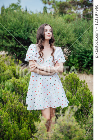 Beautiful brunette woman in summer dress walking in the park 123297960