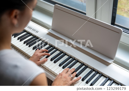 Young woman playing a keyboard at home. Music practice enhances creativity and emotional expression 123299179