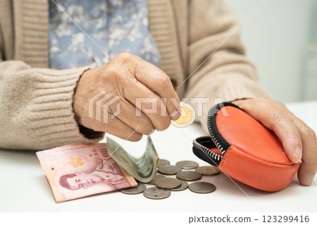 Asian senior or elderly old lady woman holding counting coin money in purse. Poverty, saving problem in retirement. 123299416