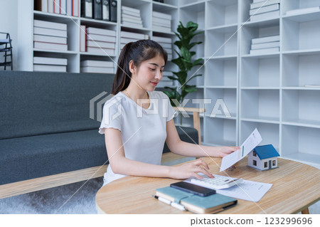 Young woman analyzing financial documents and planning home investment at modern coffee table in stylish living room Young woman analyzing financial documents and planning home investment at modern coffee table in stylish living room 123299696