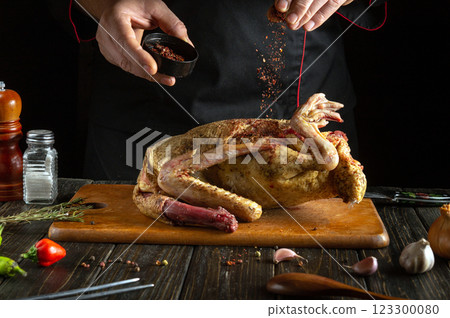 Cooking duck on the kitchen table. For aroma and taste, the chef adds dry spices to the bird carcass before roasting. Delicious duck for the festive table by the hands of the cook. Cooking duck on the kitchen table. For aroma and taste, the chef adds dry spices to the bird carcass before roasting. Delicious duck for the festive table by the hands of the cook. 123300080