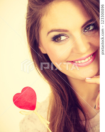 Flirty woman holding red wooden heart on stick 123300896