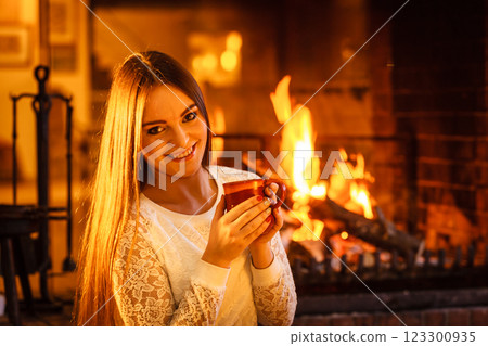Woman drinking hot coffee relaxing at fireplace. 123300935