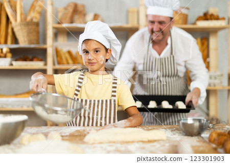 Daughter works with her father, sifts flour in kitchen next to table Daughter works with her father, sifts flour in kitchen next to table 123301903