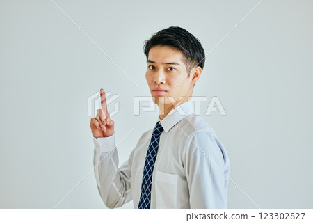 A young man in a dress shirt pointing up 123302827
