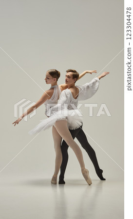 Ballet partners moving in perfect harmony, arms extended with fluid motion, bodies intertwining in elegant balance against white studio background. Ballet partners moving in perfect harmony, arms extended with fluid motion, bodies intertwining in elegant balance against white studio background. 123304478