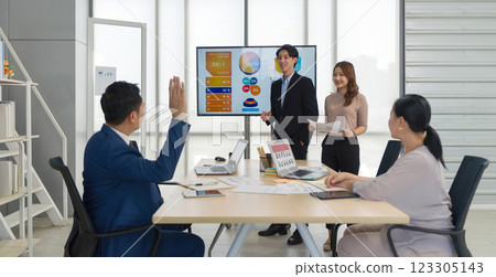 Senior asian businessman in suit raise his hand to ask a question to presenter standing in front of a large digital monitor. Business executive team meeting in modern office. Senior asian businessman in suit raise his hand to ask a question to presenter standing in front of a large digital monitor. Business executive team meeting in modern office. 123305143