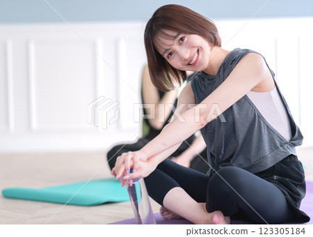 坐在瑜珈墊上拿著塑膠瓶的年輕女子 123305184