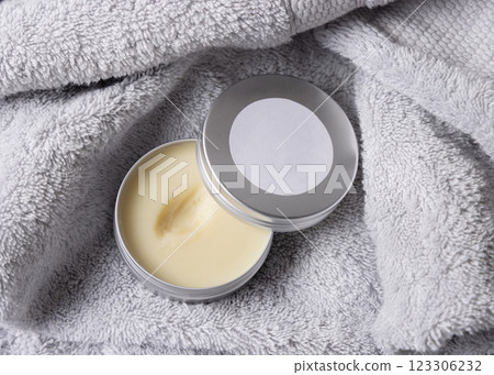 Opened body butter jar with blank label on light grey bath towel close up, cosmetic mockup 123306232
