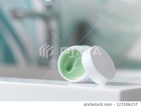 Opened white blank lip balm jar on wash basin in green tropical bathroom close up, cosmetic mockup Opened white blank lip balm jar on wash basin in green tropical bathroom close up, cosmetic mockup 123306237
