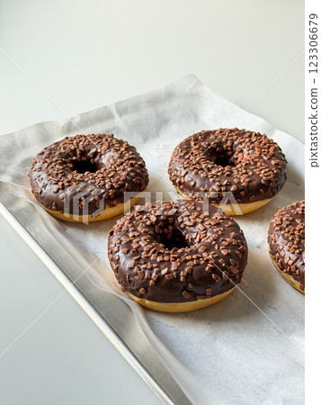 Brown chocolate donuts on metal tray and white table top view Brown chocolate donuts on metal tray and white table top view 123306679