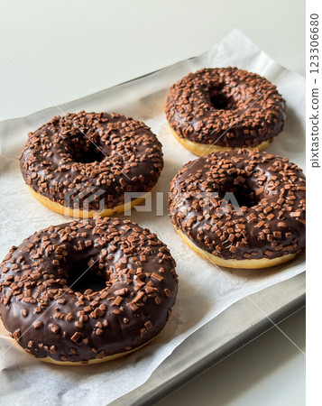 Brown chocolate donuts on metal tray and white table side view 123306680