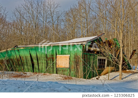 Old green barn collapses due to age and heavy snow load in winter 123306825