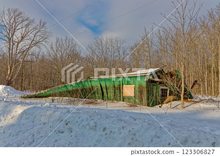 Old green barn collapses due to age and heavy snow load in winter 123306827